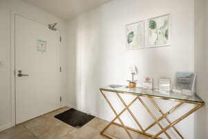 Een nette, moderne receptie met een glazen toonbank, een zwarte deurmat en twee ingelijste botanische prints aan de muur.