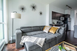 Een moderne woonkamer met een grijze bank, een vloerlamp en een salontafel.