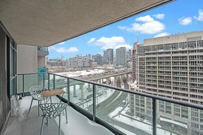 Un balcón con vistas a un paisaje urbano, incluyendo un puente y edificios altos.
