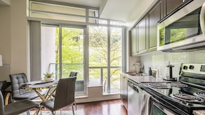 Uma cozinha moderna com uma janela grande, uma área de jantar com mesa redonda e cadeiras, e um fogão embutido.