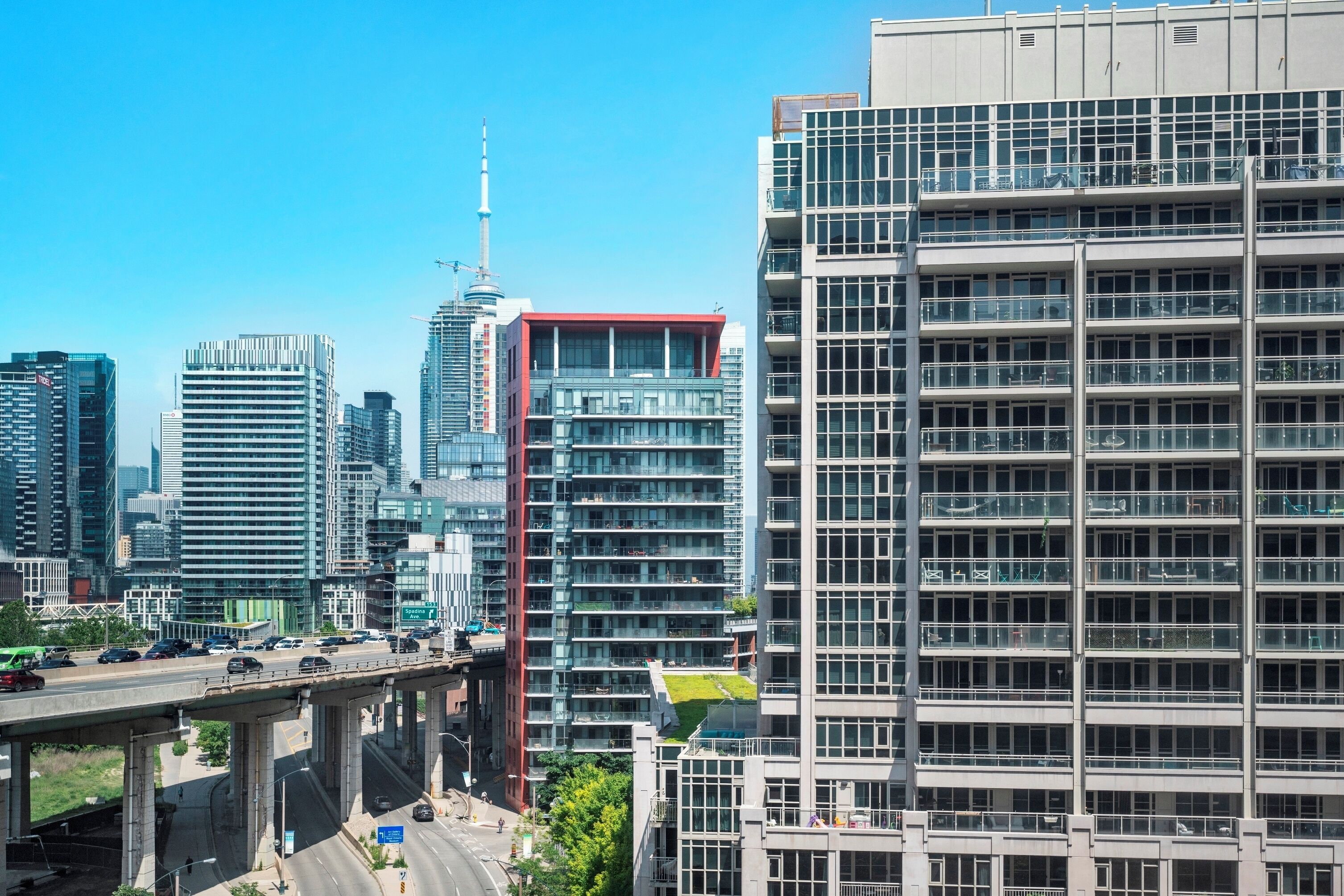 A modern urban skyline with high-rise buildings, including a distinctive red and blue building, and a highway with vehicles.