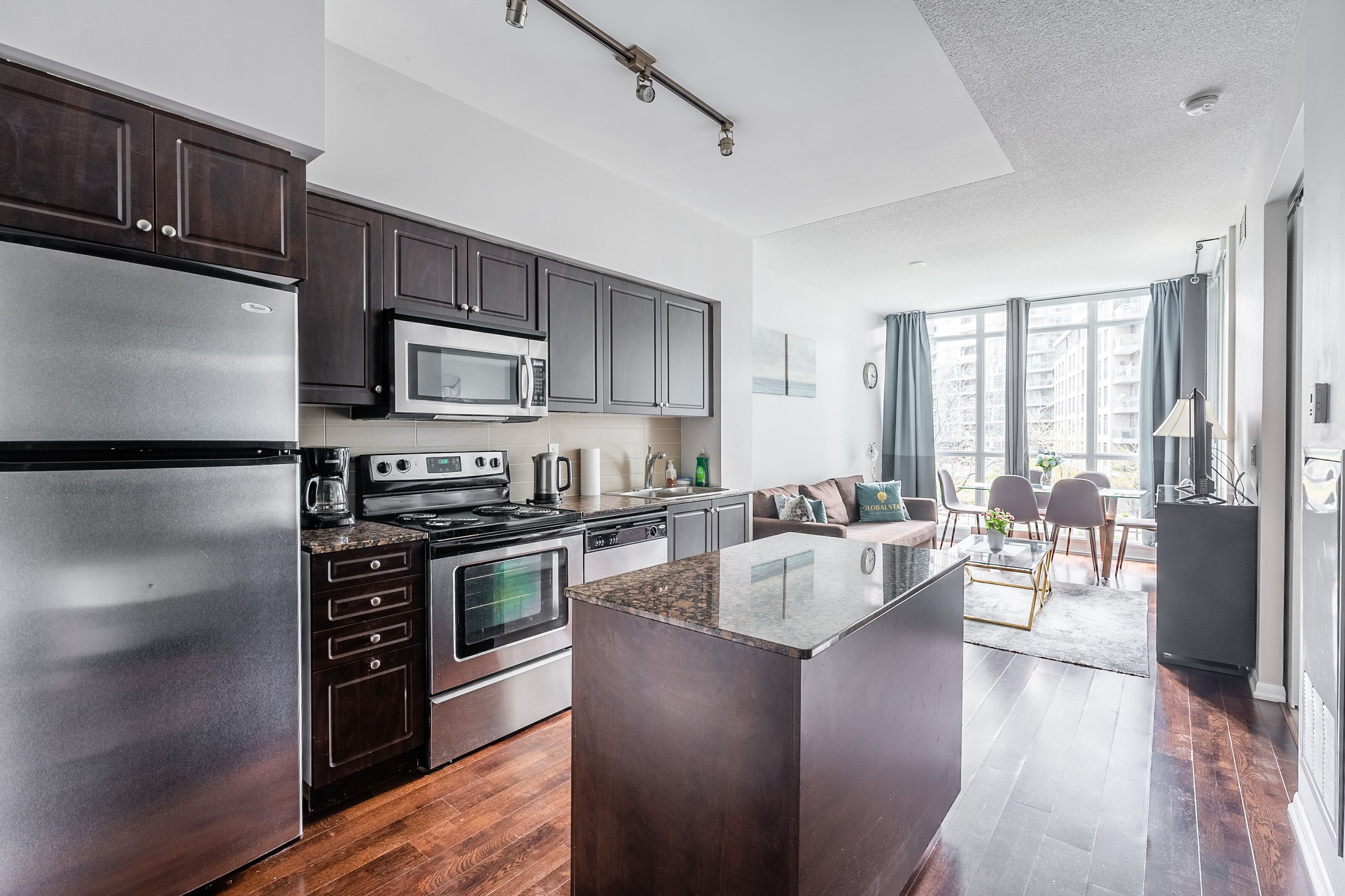 Una cocina moderna con armarios oscuros, electrodomésticos de acero inoxidable y una isla grande.