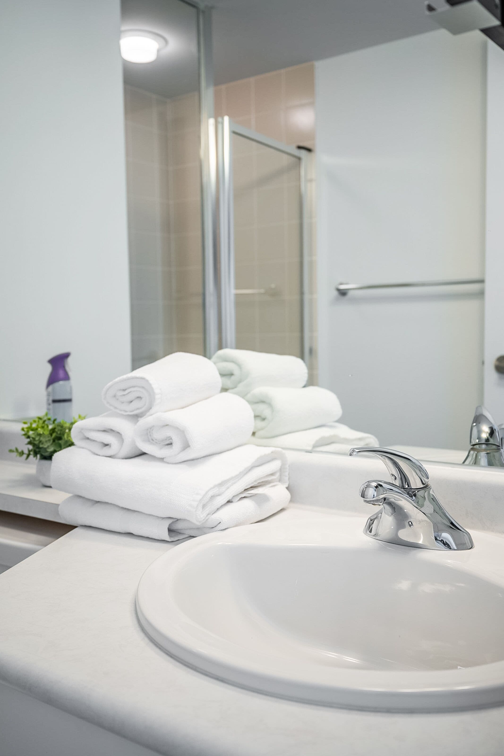 A bathroom with a white sink, a mirror, and a glass shower enclosure.