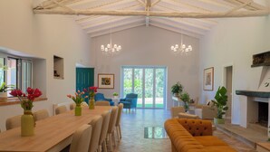 A spacious living area with a high ceiling, a wooden dining table, and a large sofa. - Villa Cammà (Mirto)
