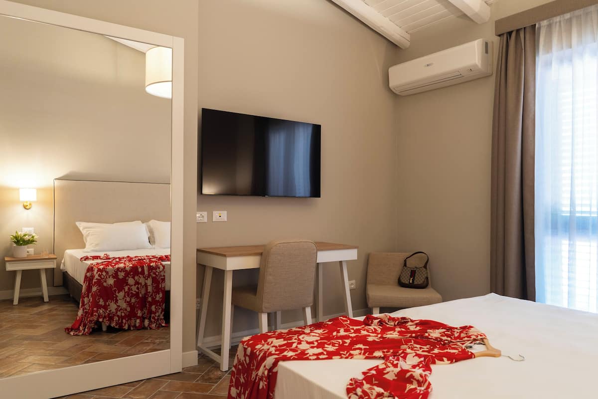 Une chambre d’hôtel équipée d’un lit, d’un bureau, d’une chaise, d’une télévision, d’un climatiseur et d’une fenêtre avec des rideaux.