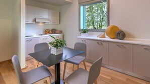 Une cuisine moderne avec une table à manger, des chaises et une fenêtre donnant sur les arbres.