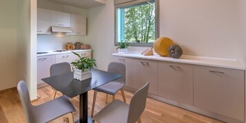Una cocina moderna con una mesa de comedor, sillas y un ventanal con vista a árboles.
