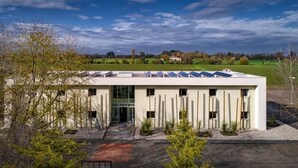 Un bâtiment moderne doté d’un toit plat, de panneaux solaires et d’une façade symétrique.