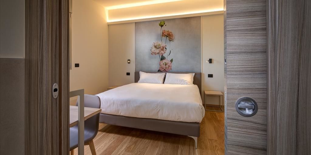 Una camera da letto moderna con un letto, comodini, una sedia e un'opera d'arte appesa al muro.