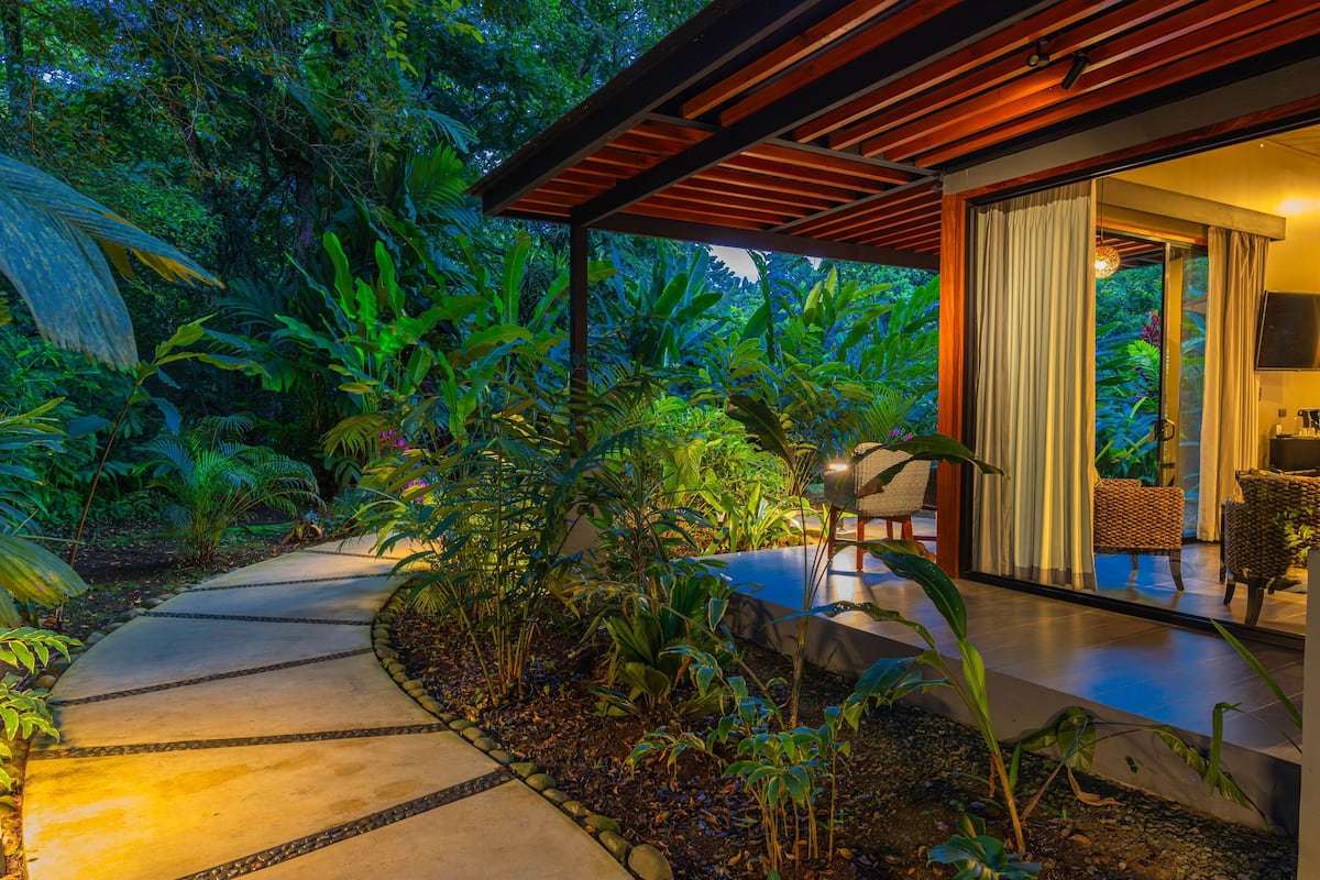 A pathway leading to a covered outdoor area with a wooden ceiling and a glass door.