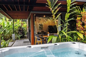 Ein Whirlpool unter einer hölzernen Pergola, umgeben von üppiger tropischer Vegetation.