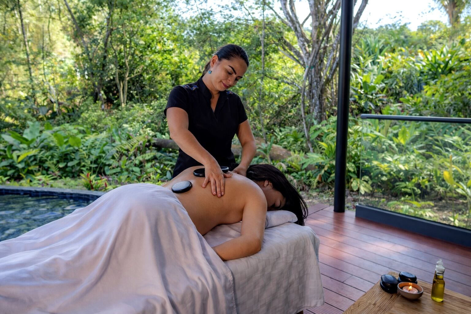 Eine Massage im Grünen, in einer üppigen Gartenanlage mit Holzterrasse und Blick auf dichtes Grün.