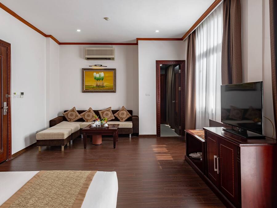 A hotel room with a bed, a sofa, a TV, and a coffee table.