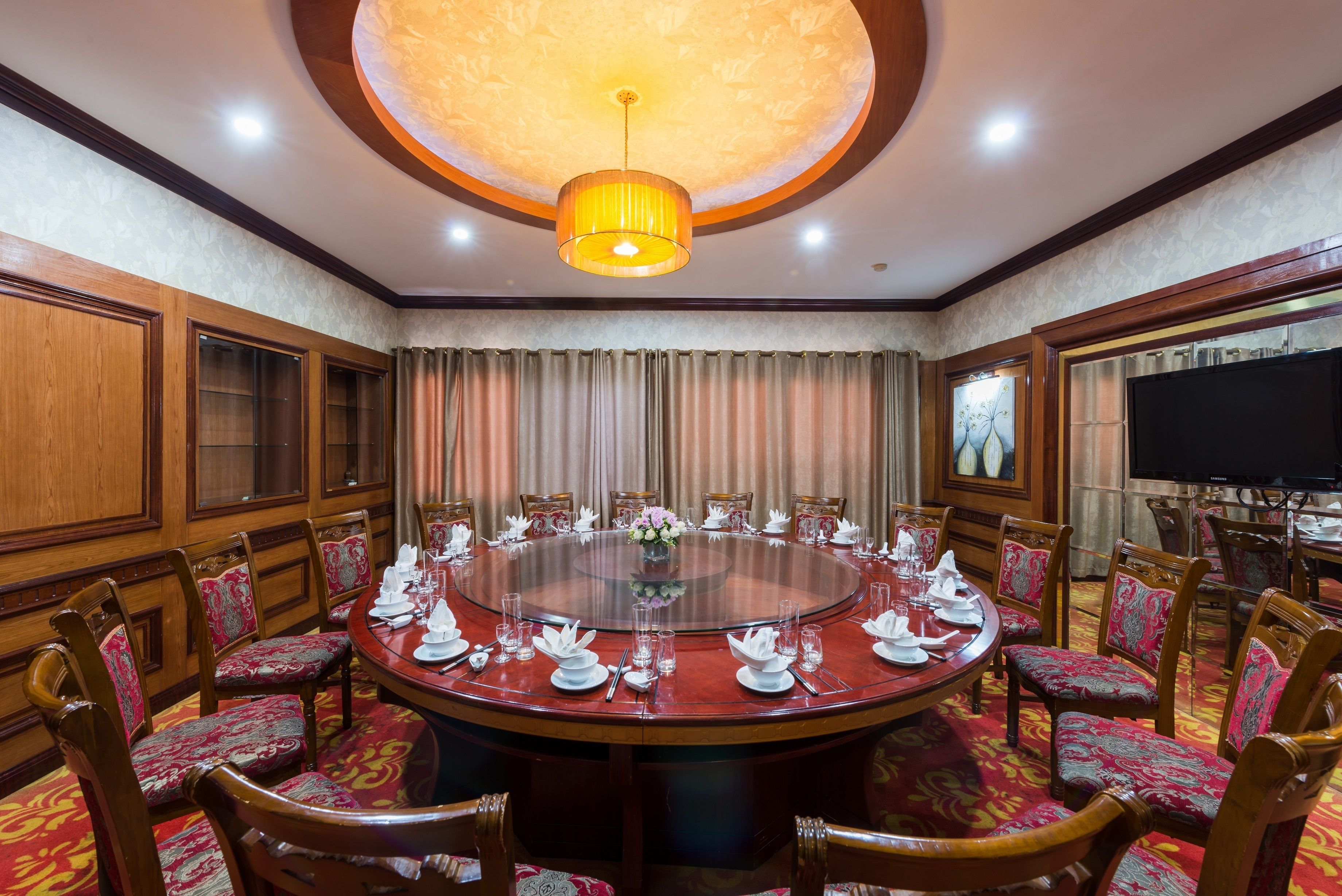 A conference room with a round table, chairs, and a television screen.