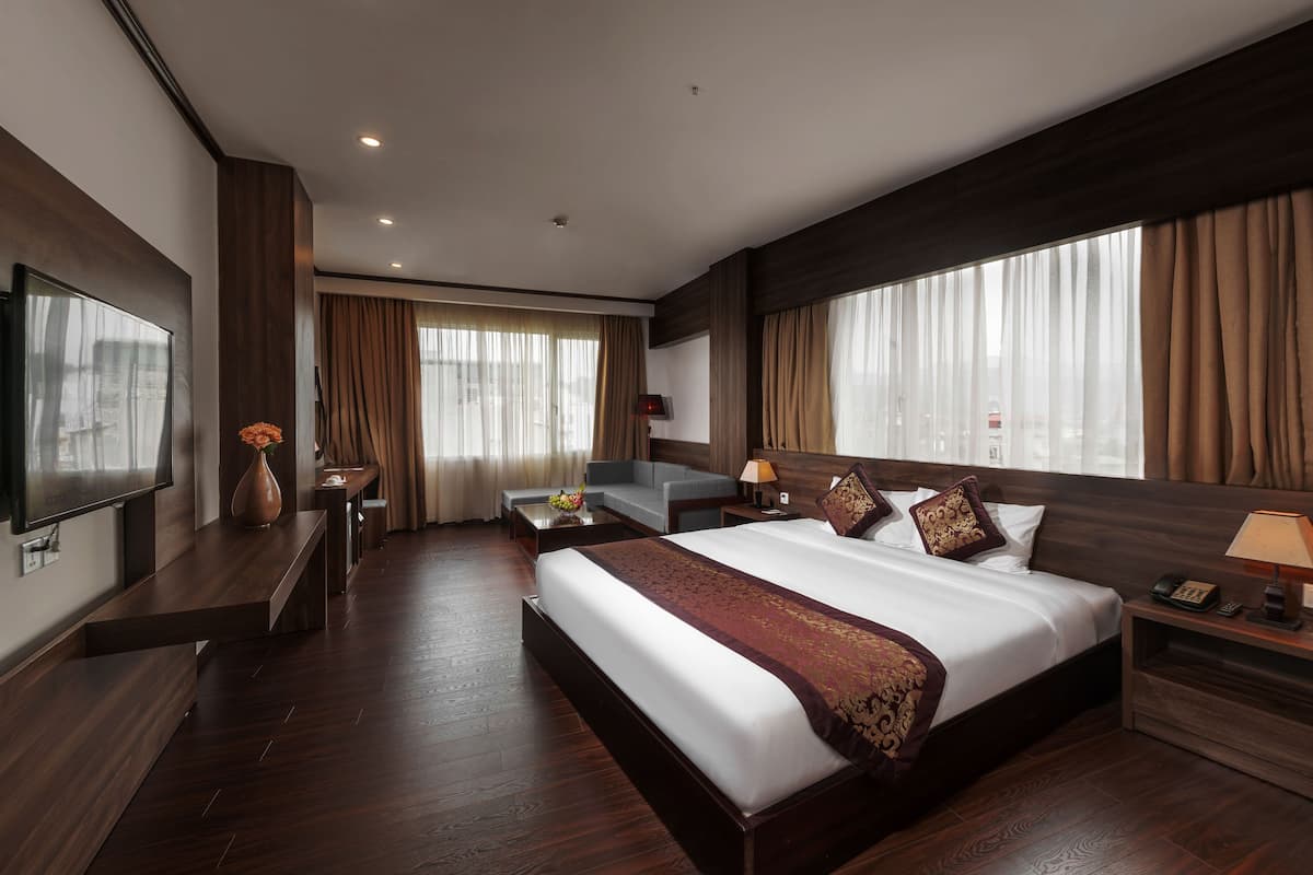 Una habitación de hotel con una cama grande, televisión, escritorio y sofá.