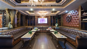 A luxurious room with a large seating area, a chandelier, and a screen displaying a rose.
