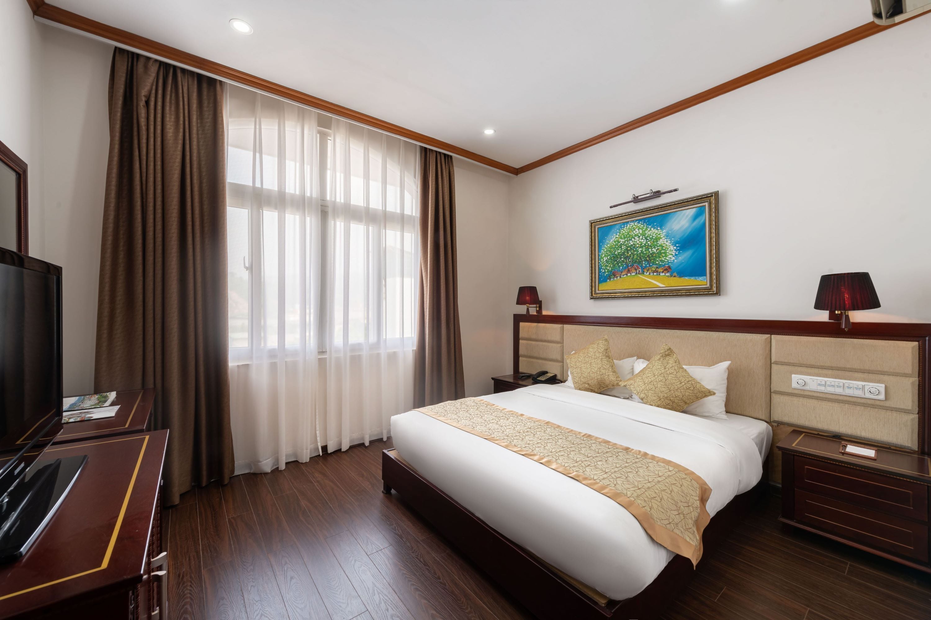 Una habitación de hotel con una cama grande, televisión, escritorio y un cuadro en la pared.