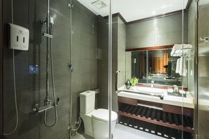 Un baño moderno con cabina de ducha de vidrio, inodoro, lavamanos con espejo y toallero.