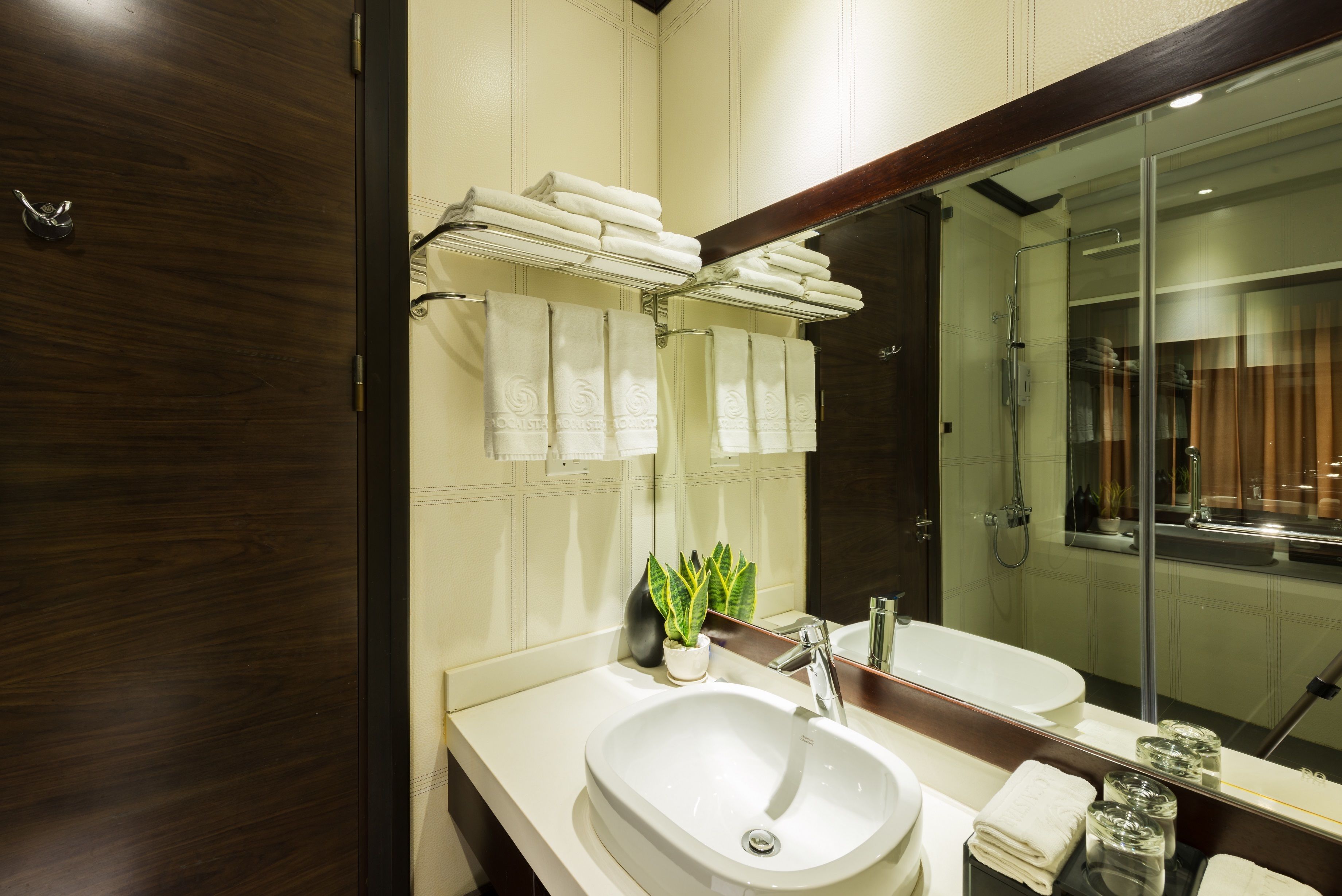 A modern bathroom with a large mirror, a white sink, and a glass shower enclosure.