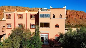 A building with a reception area, multiple windows, and a mountainous backdrop. - Hotel Boutaghrar (Ighil N'Oumgoun)