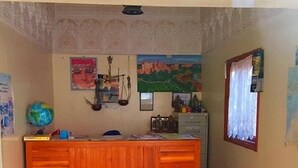 A reception area with a wooden desk, a globe, and a painting on the wall. - Hotel Boutaghrar (Ighil N'Oumgoun)