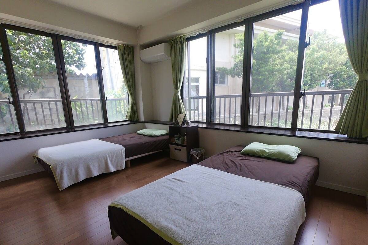 A hotel room with two beds, a small table, and a window with curtains.