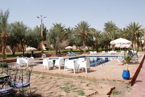 Alberca al aire libre, sombrillas en la alberca y camastros