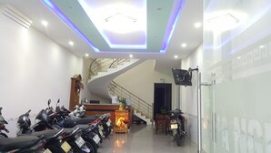 A modern interior with a staircase, ceiling lights, and a row of parked motorcycles. - Motel Thanh Long (Da Nang)