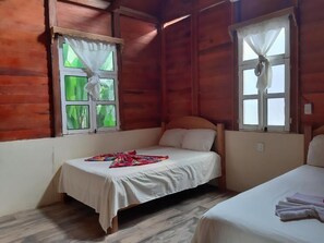Ein Zimmer mit zwei Betten, Holzwänden und Fenstern mit Vorhängen.
