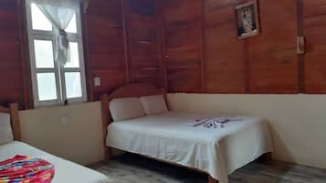 Habitación de cabaña de madera con una cama individual, una ventana con cortinas y un cuadro en la pared.