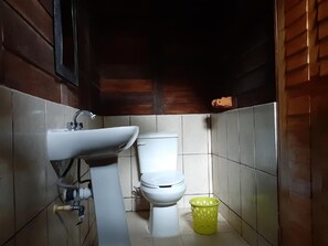Ein kleines Badezimmer mit Waschbecken, Toilette und einem gelben Mülleimer.