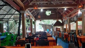 Un restaurante con mesas y sillas al aire libre, cubierto por un techo.