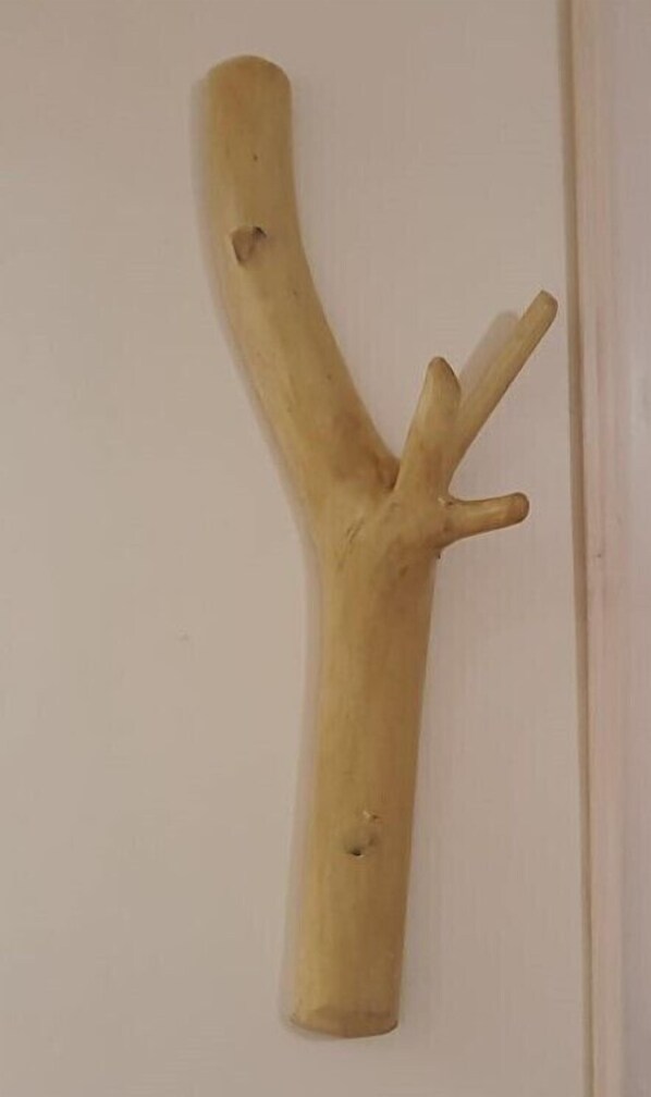 Una escultura de madera con una rama curvada y tres elementos sobresalientes.