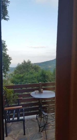 Un patio con una mesa redonda y un banco, con vistas a un paisaje montañoso.