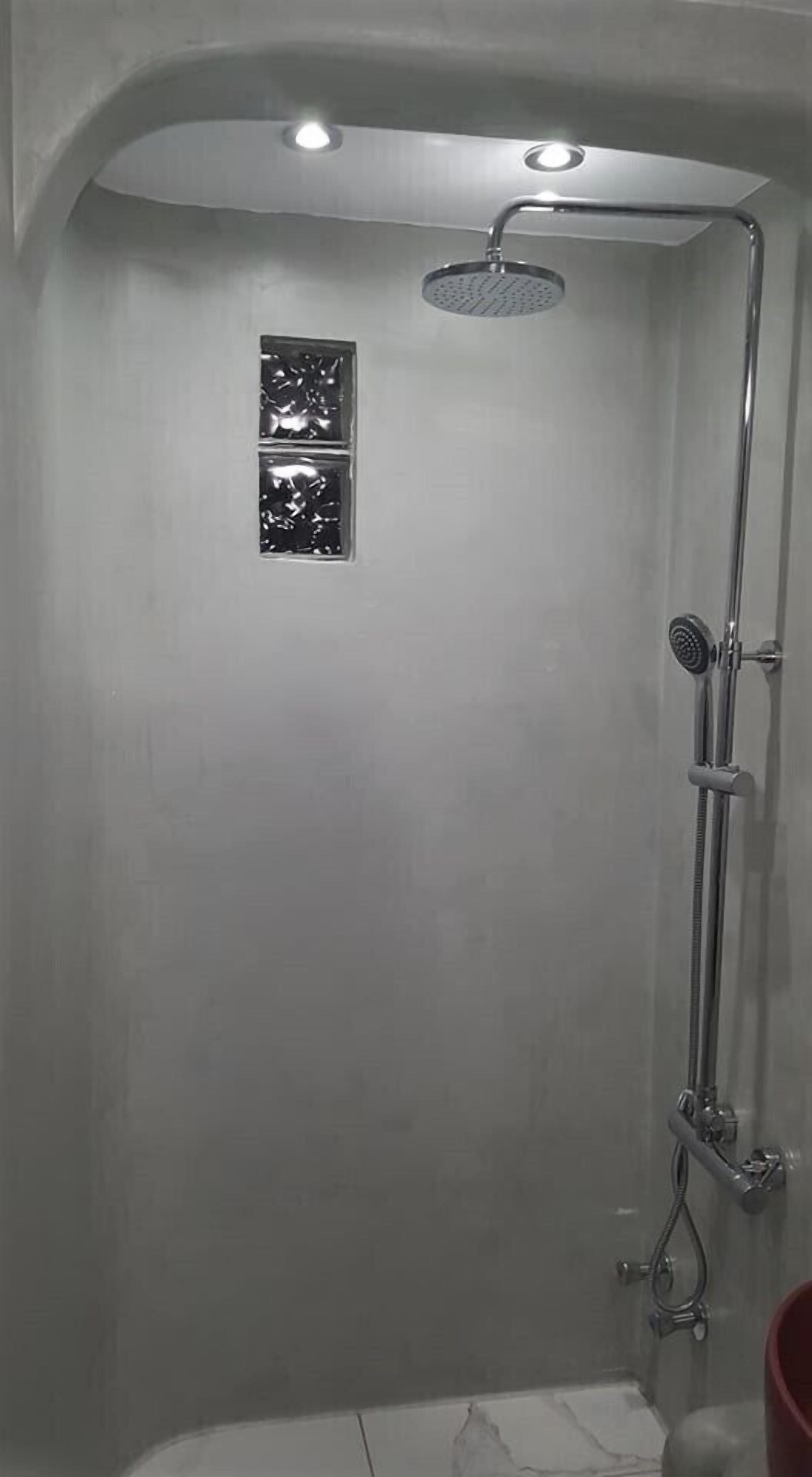 Ducha con cabezal de ducha de mano, grifo empotrado y una ventana pequeña.