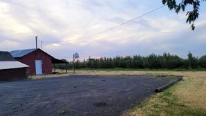Un entorno rural con un granero rojo, un aro de baloncesto y un estacionamiento de grava.