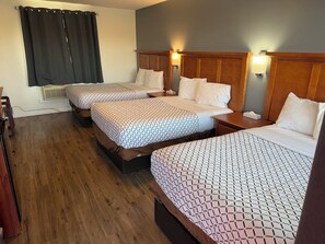 A hotel room with three beds, wooden headboards, and bedside lamps. - Out West Motel (Milton-Freewater)