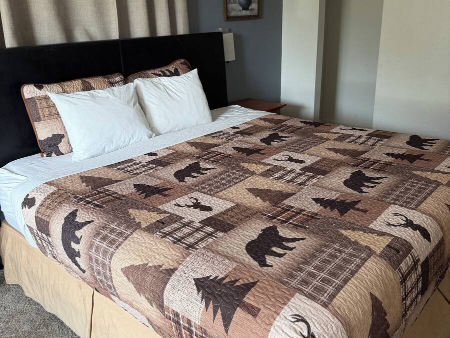 Une chambre d’hôtel avec un grand lit, une tête de lit, une table de chevet, un tableau au mur et une armoire.