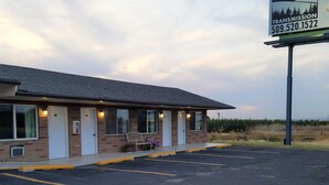 Un motel con fachada de ladrillo, un espacio de estar al aire libre cubierto y un estacionamiento.
