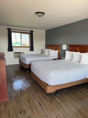 A hotel room with two beds, a window with curtains, a wooden headboard, and a ceiling light. - Out West Motel (Milton-Freewater)