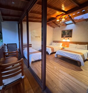 Habitación con dos camas, suelo y techo de madera, y ventana con vistas a un paisaje natural.