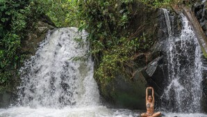 A waterfall with a person sitting in the water.