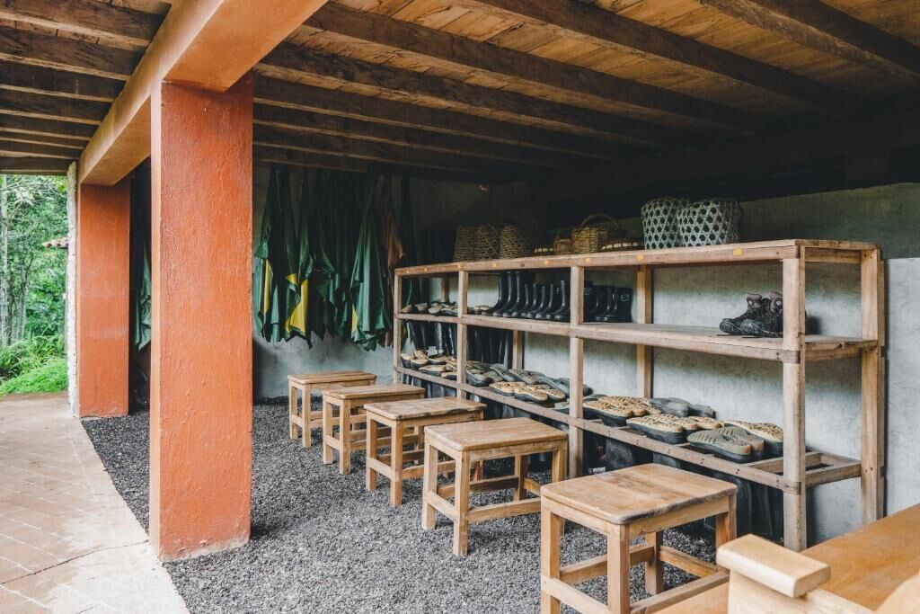 Ein rustikaler Holzraum mit Kiesboden, Holzbanken und Regalen mit Schuhen und Körben.