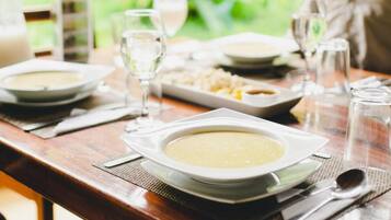 A dining table set with plates of soup, glasses of water, and cutlery.