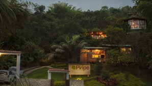 A wellness lodge named 'Piripe' with a sign, surrounded by lush greenery and a well-maintained garden.