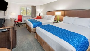Habitación de hotel con dos camas, un escritorio, una silla y un televisor.