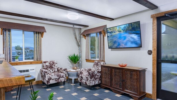 Una habitación acogedora con un banco de madera, dos sillones estampados, una mesita y un armario.