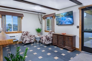Um quarto aconchegante com um banco de madeira, duas poltronas estampadas, uma pequena mesa e um armário.