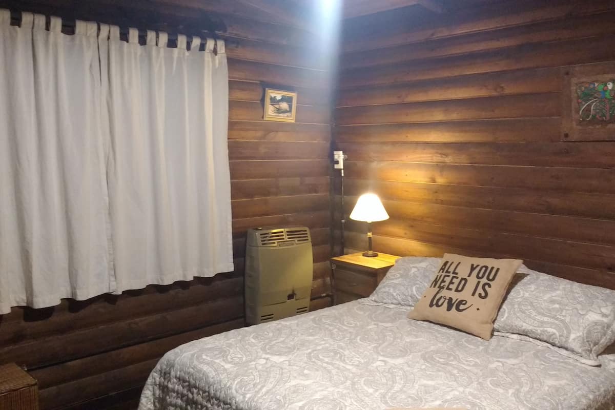 A cozy room with a bed, a nightstand, a lamp, and a pillow with a motivational quote.
