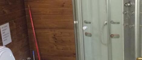 A bathroom with two toilets, a shower enclosure, and wooden walls.